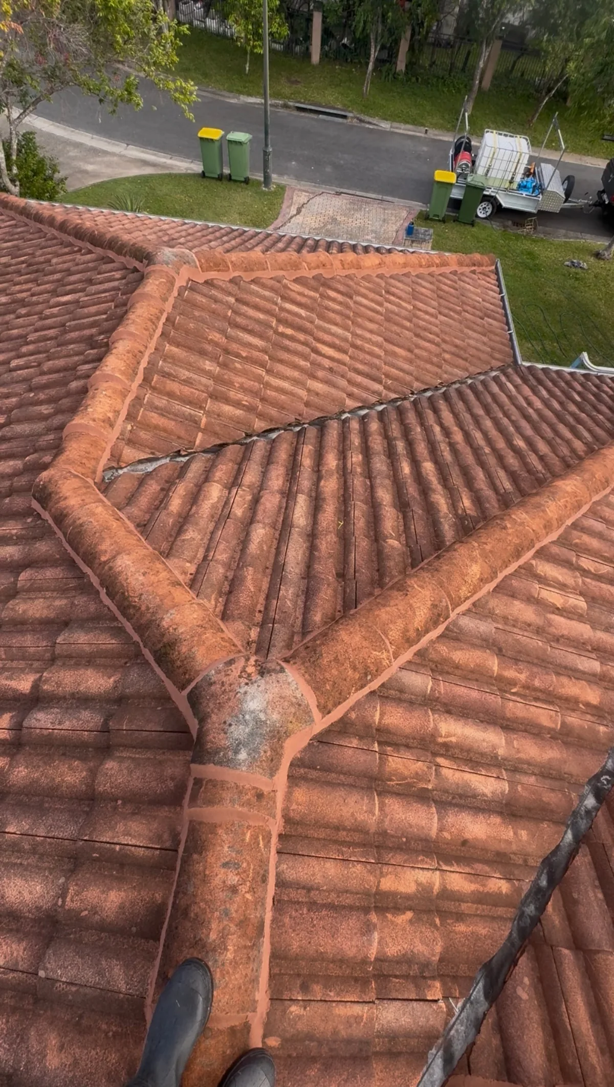 Terracotta roof hips and valleys stained with grime and moss — before